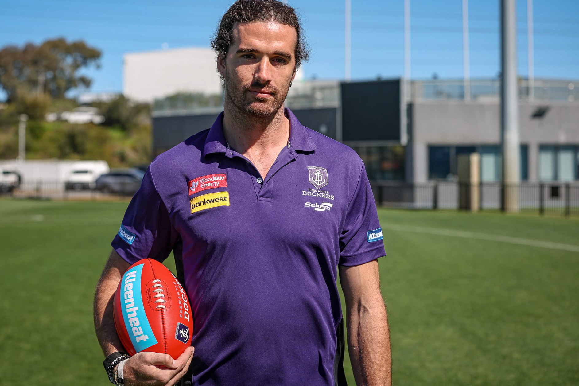 photo of a footballer in football clothes and holding a football 