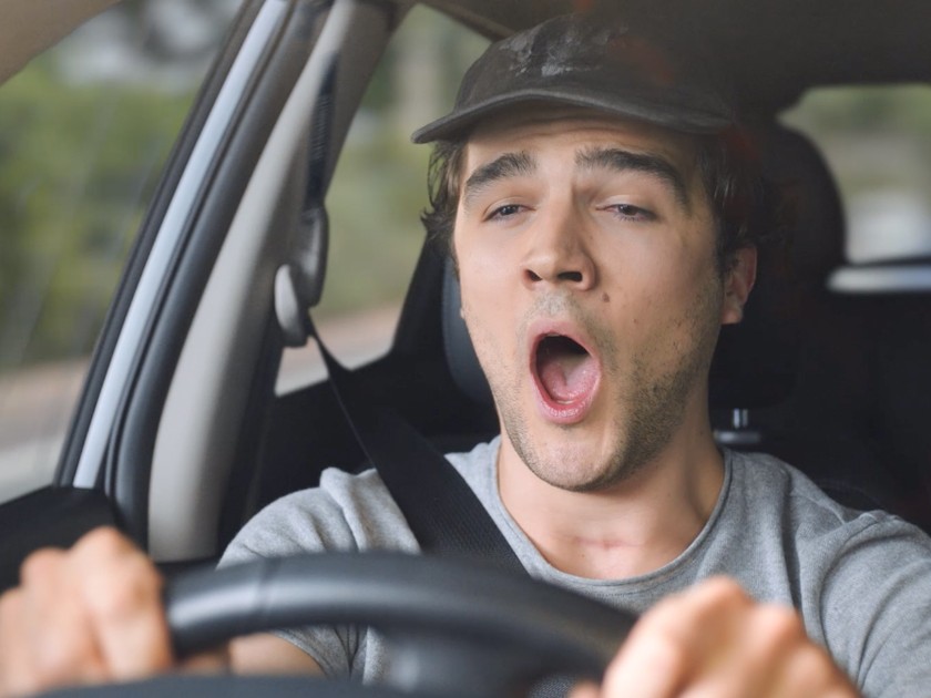 A man yawning behind the wheel of a car