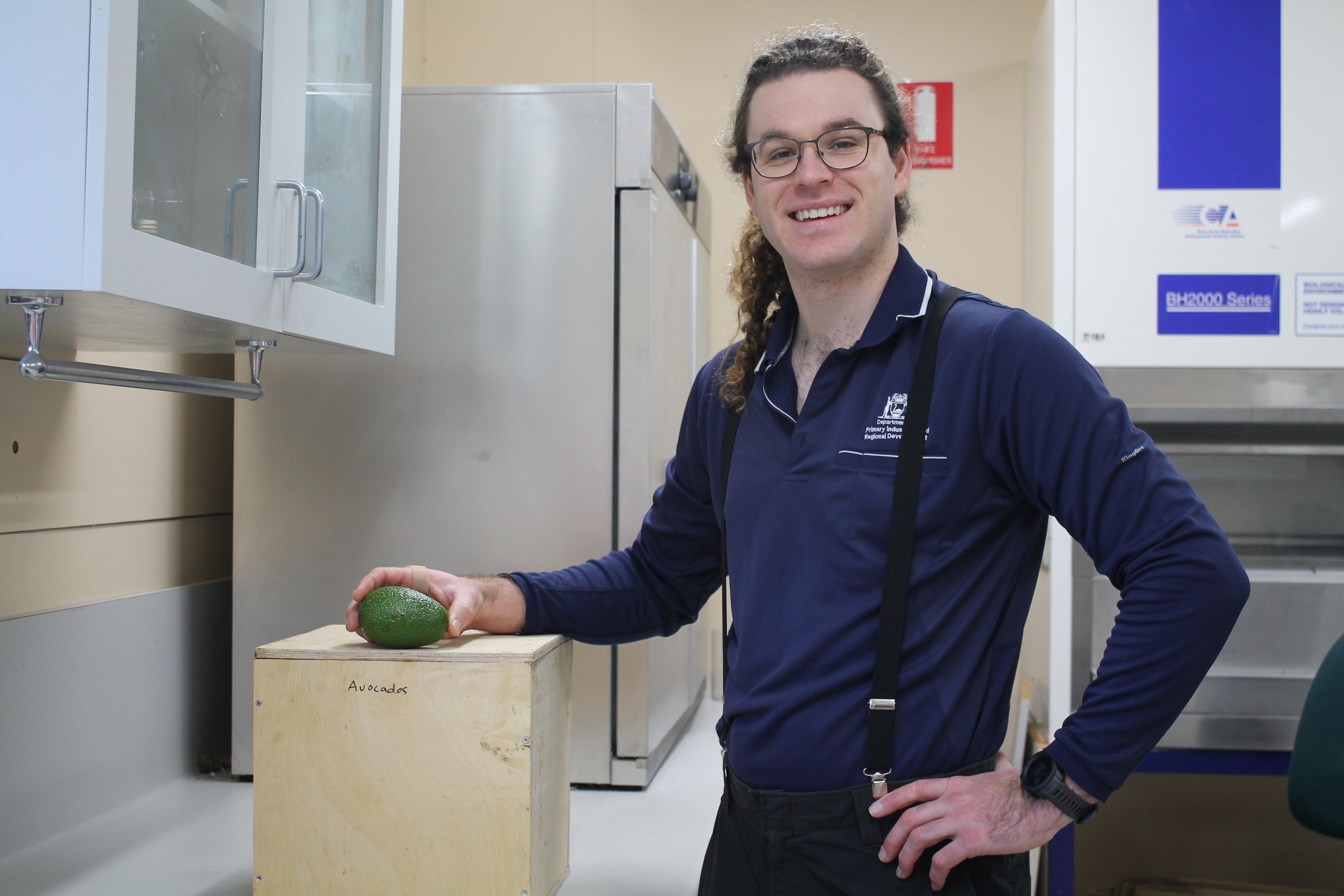DPIRD research scientist Declan McCauley in lab holding an avocado